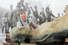 Dietrich Timm nimmt Schleifarbeiten an einem Material-Riss an der Figur «Kämpfer mit Decke» des Buchenwald-Mahnmals von Fritz Cremer in der Restaurierungswerkstatt in Weimar vor. Im Hintergrund hängt ein Schwarz-Weiss-Bild des Mahnmals. Ursprünglich sollte die Plastik nach drei Jahren Restaurierung am 11. April 2005, dem 60. Jahrestag der Befreiung des KZ Buchenwald, wieder aufgestellt werden. Durch die schwierige Verankerung der elf Bronzefiguren auf ihrem Sockel verzögert sich dieser Termin. (Foto: ddp)