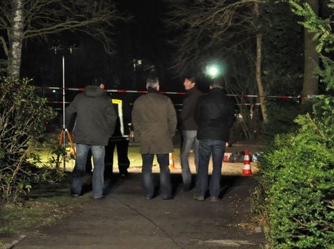 Schaulustige und ein Feuerwehrmann stehen am Donnerstag auf dem Südfriedhof in Recklinghausen hinter Absperrband vor der Leiche eines Mannes. (FOTO: DAPD)
