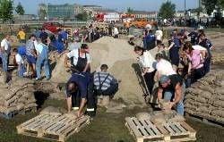 Helfer füllen im August 2002 Sandsäcke zum Schutz des Chemieparks in Bitterfeld (Archivfoto: MZ)