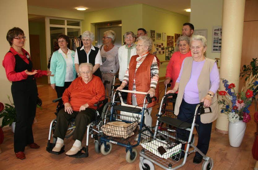Corinna Trebbin (l.) begleitet Seniorinnen und Mitarbeiter beider Pflegeheime beim Rundgang durch das Jessener Haus.