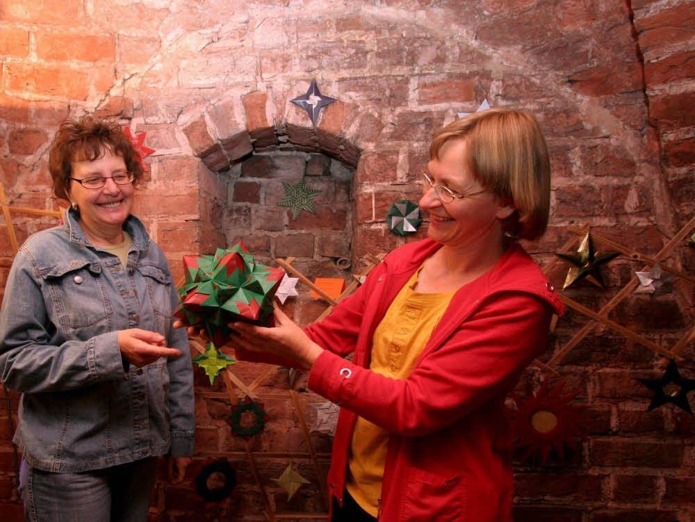 Angela Demele (links) und Eva-Maria Glüer bauen unterstützt von mehreren Helfern die Ausstellung unter dem Titel „Faszination Papier“ in der 700 Jahre alten Stadtkirche von Prettin auf.