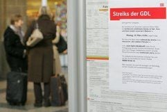 Hinter einem Aushang der Deutschen Bahn, der über die geplanten Streiks bei der Gewerkschaft der Lokomotivführer GDL hinweist, unterhalten sich im Hauptbahnhof in Hagen drei Reisende. (Foto: dpa)