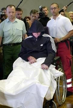 Der angeklagte Thorsten V. wird am Dienstag (20.05.2003) von Sanitätern und Justizbeamten in einem Spezialrollstuhl zur Urteilsverkündung in den Gerichtssaal des Landgerichts in Gießen gebracht. Er wurde vom Gericht zu einer lebenslangen Haftstrafe verurteilt. Der von schweren Brandverletzungen gezeichnete Angeklagte soll am 29. Juni 2001 versucht haben, die achtjährige Julia aus dem mittelhessischen Biebertal sexuell zu missbrauchen. Um die Misshandlung zu verdecken, habe der 35 Jahre alte Familienvater das blonde Mädchen nach Auffassung der Staatsanwaltschaft noch am Abend der Entführung erschlagen. Während des mehr als sechs Monate dauernden Indizienprozesses schwieg der Angeklagte zu den Tatvorwürfen. (Foto: dpa)