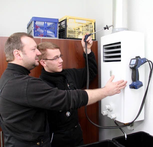 Bezirksschornsteinfeger André Klaus Eichler und sein Auszubildender Norman Könnecke überprüfen eine Gastherme.