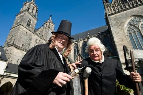 Die Laiendarsteller Volkmar Emcke (l.) als Doktor Eisenbart und Joachim Bachmann als Famulus stehen vor dem Dom in Magdeburg. Auf dem Messeplatz im Magdeburger Stadtpark beginnt am Samstag die Herbstmesse. (FOTO: DPA)