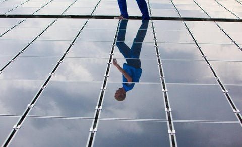 Der Schatten eines Mitarbeiters spiegelt sich in einem Solarmodul. (FOTO: DPA)