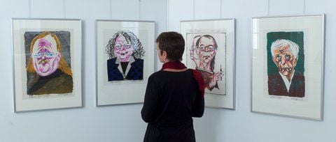 Die Porträtkarikaturen über (l-r) Peter Sloterdijk (2002), Ingo Schulze (2006), Volker Braun (2006) und Ernst Jünger (2006) von Harald Kretzschmar schaut sich die Papierrestauratorin Franziska F. Pucher in den Ausstellungsräumen des Sommerpalais der Staatliche Bücher- und Kupferstichsammlung Greiz an (FOTO: DPA)