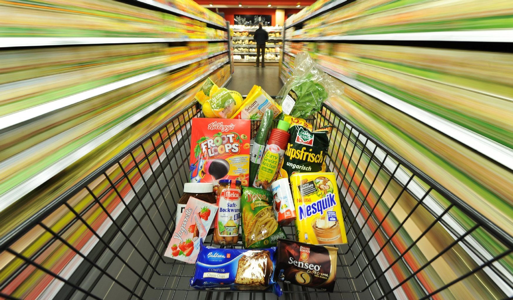 Ein Einkaufswagen mit Lebensmitteln steht in einem Supermarkt.