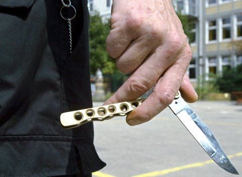 Ein Mann hält ein Klappmesser in der Hand.