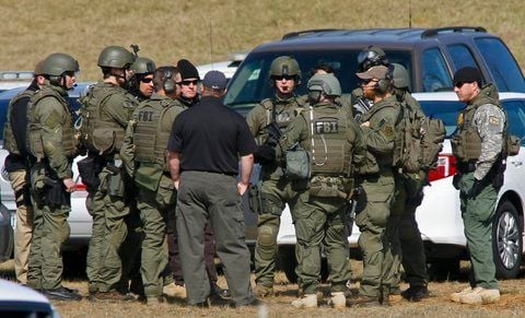 Bewaffnete Polizisten der US-Bundespolizei FBI beraten sich nahe dem unterirdischen Bunker in Midland City, wo sich der 65-jähriger Vietnamkriegsveteran mit dem Kind verschanzt hat. (FOTO: RTR)