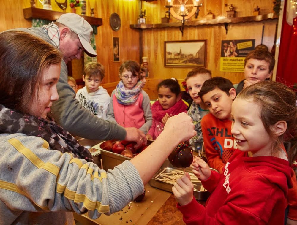 Marktmeister Hendrik Lerpscher lud Kinder der Grundschule Regenbogen in seine Glühweinhütte auf dem Heele-Christ-Markt ein, wo sie Obst selbst kandieren durften.