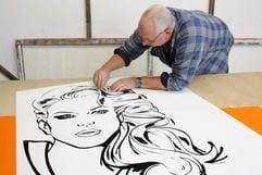 Der Chef der Firma Werner-Werbung, Michael Werner, in seiner Werkstatt in Berlin bei der Arbeit an einem Frauenkopf für eine Außenwerbung. (Foto: dpa)