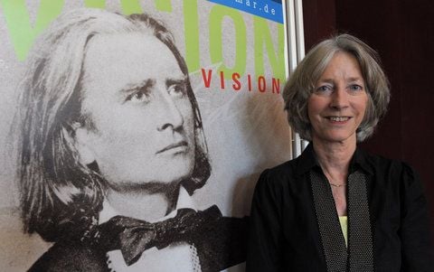 Die künstlerische Leiterin Nike Wagner steht in Weimar neben einem Veranstaltungsplakat zum Kunstfest Weimar mit dem Bildnis Franz Liszts. (FOTO: DPA)