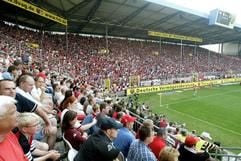Das vollbesetzte Fritz-Walter-Stadion des 1. FC Kaiserslautern (Archivfoto vom 02.08.2003). Vorn die Südtribüne, rechts hinten die Westkurve mit den FCK-Fans. Klein, aber fein, liebenswert und fußballverrückt: Mit dieser Selbstbeschreibung wirbt die mit 100.000 Einwohnern kleinste der zwölf deutschen WM-Städte für das größte Fußball-Ereignis in der Geschichte der pfälzischen «Metropole» Kaiserslautern. Die Tradition der Fußball-Stadt mit dem Bundesliga- Gründungsmitglied und Aushängeschild 1. FC Kaiserslautern wurde mit der Vergabe von vier Vorrundenspielen und einer Partie des WM-Achtelfinales hinreichend belohnt. (Foto: dpa)