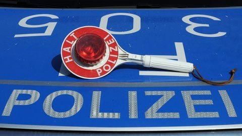 Eine Polizeikelle liegt auf der Motorhaube eines Streifenwagens.