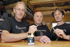 Der Vorsitzende des Vereins «Deutsche Hecke», Norman Fuhrmann (l), Pressesprecher Georg-Ove Daniel und der 2. Vorsitzende Peter Burmeister rauchen im Vereinslokal in Tönning (Kreis Nordfriesland), vor ihnen steht eine Dummy-Packung der geplanten Privat-Zigarettenmarke «Deutsche Hecke». (Foto: dpa)