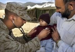 Ein Militärarzt untersucht in einem Feldlazarett für Erdbebenopfer in Shinkiari in Pakistan ein Kleinkind, das auf dem Arm seines Vaters sitzt. (Foto: dpa)