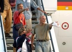 Die Sahara-Geiseln Kurt Schuster und Erna Schuster (beide links) und Jürgen Matheis (r) zeigen am Mittwochmorgen (20.08.2003) beim Aussteigen aus dem Airbus der Bundesluftwaffe, der die 14 Geiseln in der Nacht aus Bamako/Mali zurück nach Deutschland geflogen hatte, auf der Gangway auf ihre Angehörigen. (Foto: dpa)