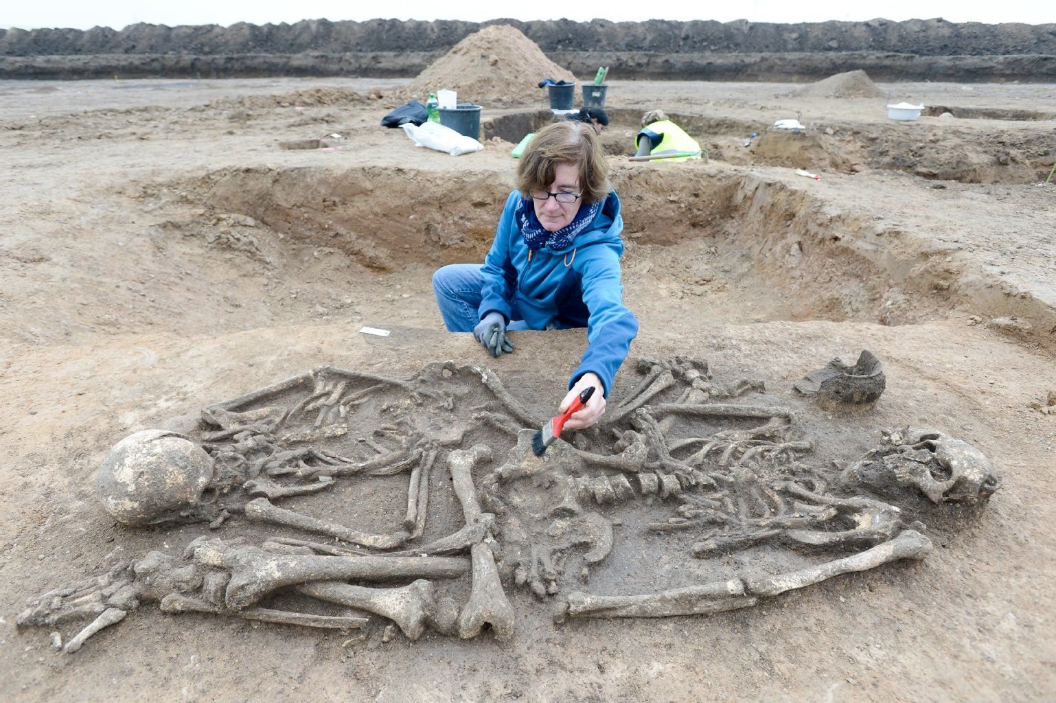 Bettina Petrick, Grabungsleiterin des Landesamtes für Archäologie und Denkmalpflege Sachsen-Anhalt, arbeitet in Karsdorf mit einem Pinsel an einem Grab mit einer Doppelbestattung.