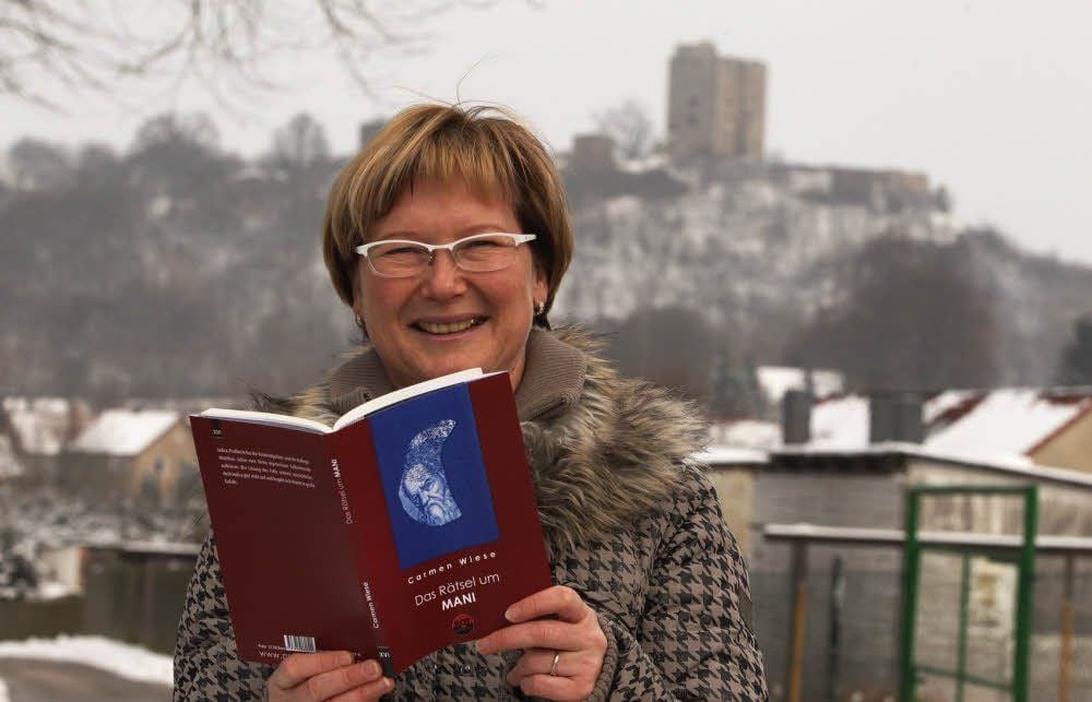 Carmen Wiese mit ihrem Erstlingswerk in Harkerode. Im Hintergrund ist die Burgruine Arnstein zu sehen, die ein wichtiger Schauplatz ist.