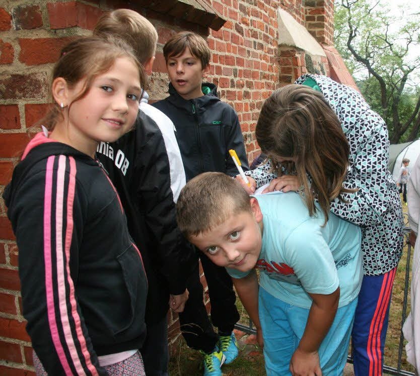 Improvisation ist alles bei den „olympischen“ Spielen auf dem Klödener Pfarrhaus- bzw. Kirchengelände: Mit Finn Luca, der hier als wandernder Schreibtisch fungiert, ist die nächste knifflige Aufgabe schnell gelöst. Insgesamt gibt es 52 davon für die drei Kinder-Teams.