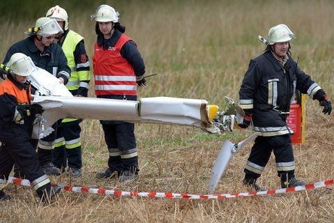 Feuerwehrleute tragen an der Absturzstelle eines Kleinflugzeuges in der Nähe des Flugplatz Steinrücken bei Coburg (Oberfranken) einen Teil einer Tragfläche. Vier Menschen sind am Sonntag beim Absturz des Kleinflugzeugs in Coburg ums Leben gekommen. (FOTO: DPA)