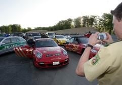 Ein Polizist fotografiert am Montag (30.04.2007) am Flughafen Hahn im Hunsrück eine Kolonne von Sportwagen, die zuvor auf der Autobahn angehalten wurden. (Foto: dpa)