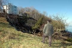 Ein älterer Mann besichtigt am Sonntag (20.03.2005) die Abbruchstelle an der Rügener Steilküste im Ort Lohme. Nach Polizeiangaben löste sich ein etwa 100 Meter langer Küstenstreifen und stürzte rund 20 Meter in die Tiefe. Verletzt wurde niemand. Die Abbruchstelle im Norden der Insel reichte bis anderthalb Meter an das Gebäude eines Betreuungsheimes für Suchtkranke (im Hintergrund) heran. Es war bereits der dritte Küstenabbruch seit Ende Februar auf Deutschlands größter Insel und nach Einschätzung von Experten einer der größten Abbrüche seit Jahrzehnten. (Foto: dpa)