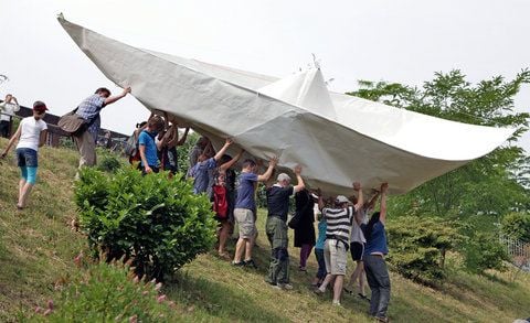 Helfer des Aktionskünstlers Frank Bölter tragen am Pfingstmontag ein überdimensionales Papierschiff zum Karl-Heine-Kanal Leipzig. (FOTO: DPA)