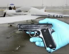 Ein Polizist zeigt vor dem Motorsegler des Typs "Super-Dimona" am Montagnachmittag (06.11.2003) auf dem Frankfurter Flughafen die Tatwaffe. Die Schreckschußpistole ist dem früheren Polizeirevolver Walther PPK nachempfunden. In diesem Flugzeug versetzte ein 31-jähriger Darmstädter mit seinem Irrflug über der Innenstadt am Sonntagnachmittag Frankfurt/Main in Angst und Schrecken. (Foto: dpa)