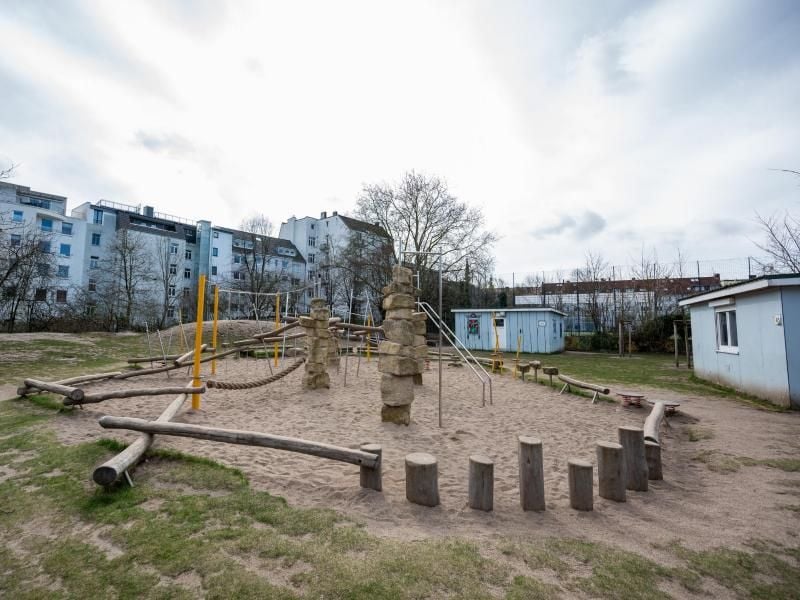 Ein menschenleererer Spielplatz auf einer Rasenfläche in Hamburg befindet sich unmitten von Häusern. Foto: Daniel Reinhardt/dpa