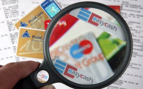 Unter einer Lupe mit der Aufschrift easycash sind Geld- und Kundenkarten zu sehen. (FOTO: DPA)