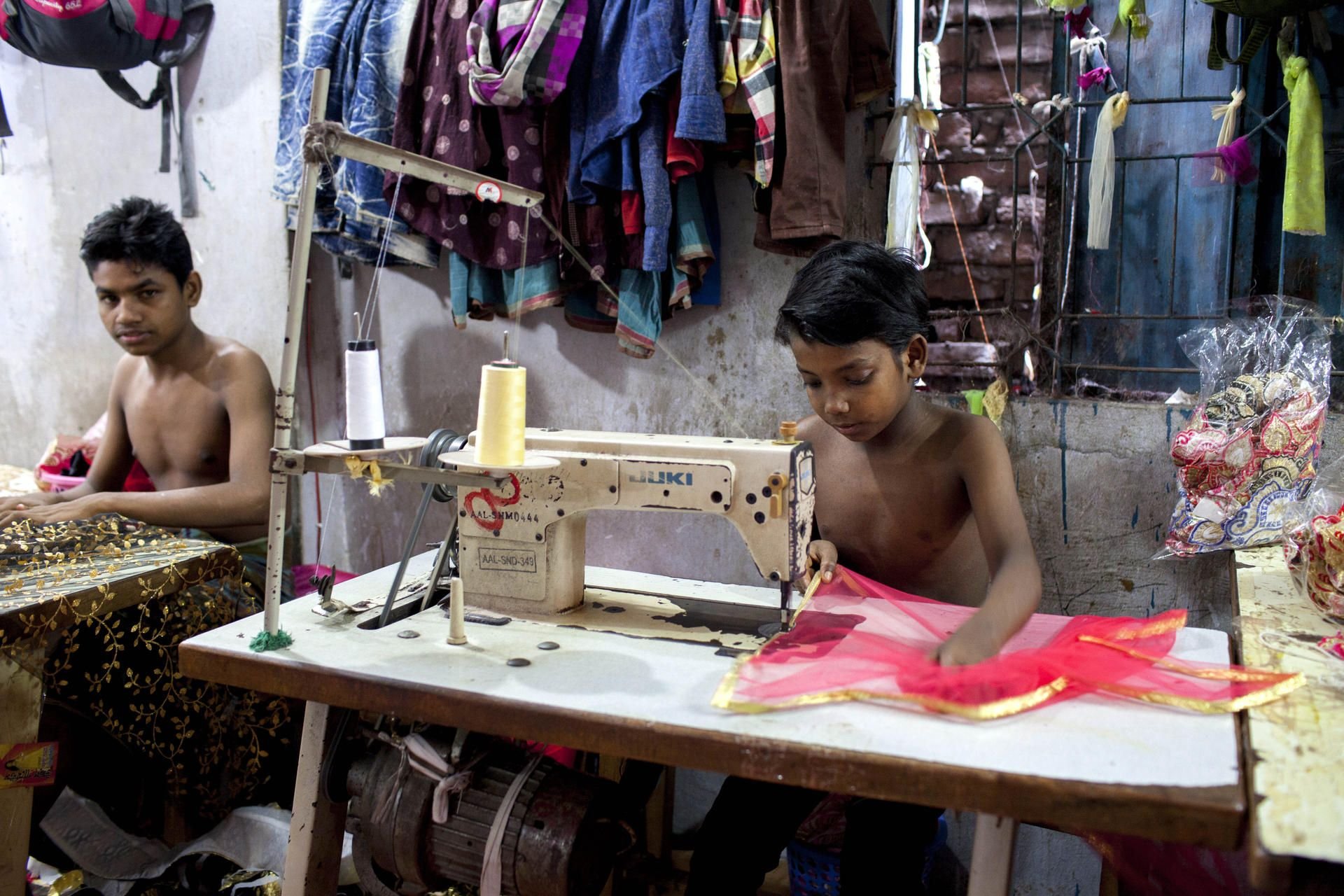 Jugendliche und Kinder arbeiten unter grausamen Bedingungen in Bangladesch an Textilwaren.