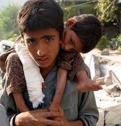 Dies sind die die im Bericht erwähnten Geschwister, doch auch sie helfen sich in der Not: Dieser Junge trägt in Muzaffarbad, im pakistanischen Teil des Kaschmir, seine verletzte Schwester. (Foto: dpa)