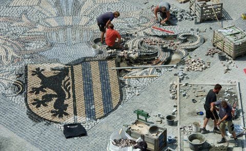 Das Stadtwappen von Leipzig fügen Bauarbeiter in die Pflasterung des Marktplatzes von Leipzig ein. (FOTO: DPA)