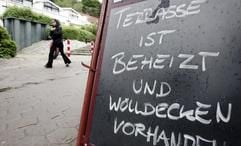 Bei grauem Wetter und frischen Temperaturen wirbt ein Straßencafe am Dienstag (23.05.2006) in Hamburg-Övelgönne mit warmen Decken um Kundschaft. Auch in den kommenden Tagen soll das Weter in Norddeutschland wechselhaft und kühl bleiben. (Foto: dpa)