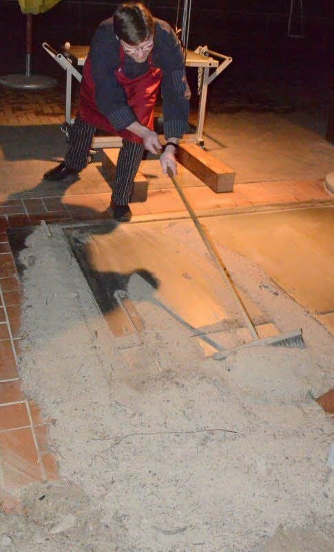 Nach viereinhalb Stunden wird der Sand weggekehrt und der Räucherofen geöffnet.