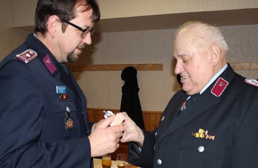 Wilfried Viehof erhielt nicht nur eine Urkunde für 60 Jahre aktives Wirken in der Feuerwehr. Klaus Unger, stellvertretender Wehrleiter, überreichte ihm auch noch eine stilisierte Spritze.