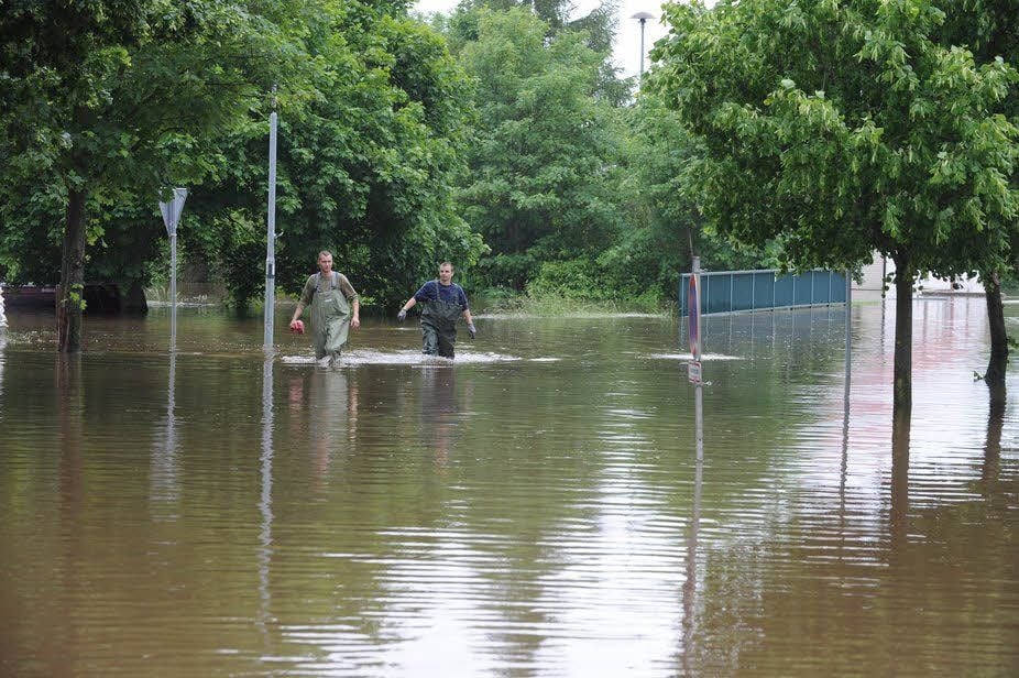 Zwei Helfer kämpfen sich durch das knietiefe Wasser.