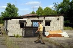 Im brandenburgischen Brieskow-Finkenheerd südlich von Frankfurt (Oder) sichert am Montag (01.08.2005) ein Polizist Spuren auf einem Hinterhof vor zwei Garagen am Fundort der neun toten Neugeborenen, die hier seit vielen Jahren in Blumentöpfen und -kästen versteckt waren. (Foto: dpa)