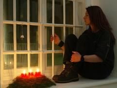 Eine inhaftierte Frau sitzt in der Vorweihnachtszeit mit einem Adventsgesteck an einem vergitterten Fenster der Justizvollzugsanstalt für Frauen in Vechta und schaut aus dem Fenster. (Foto: dpa)