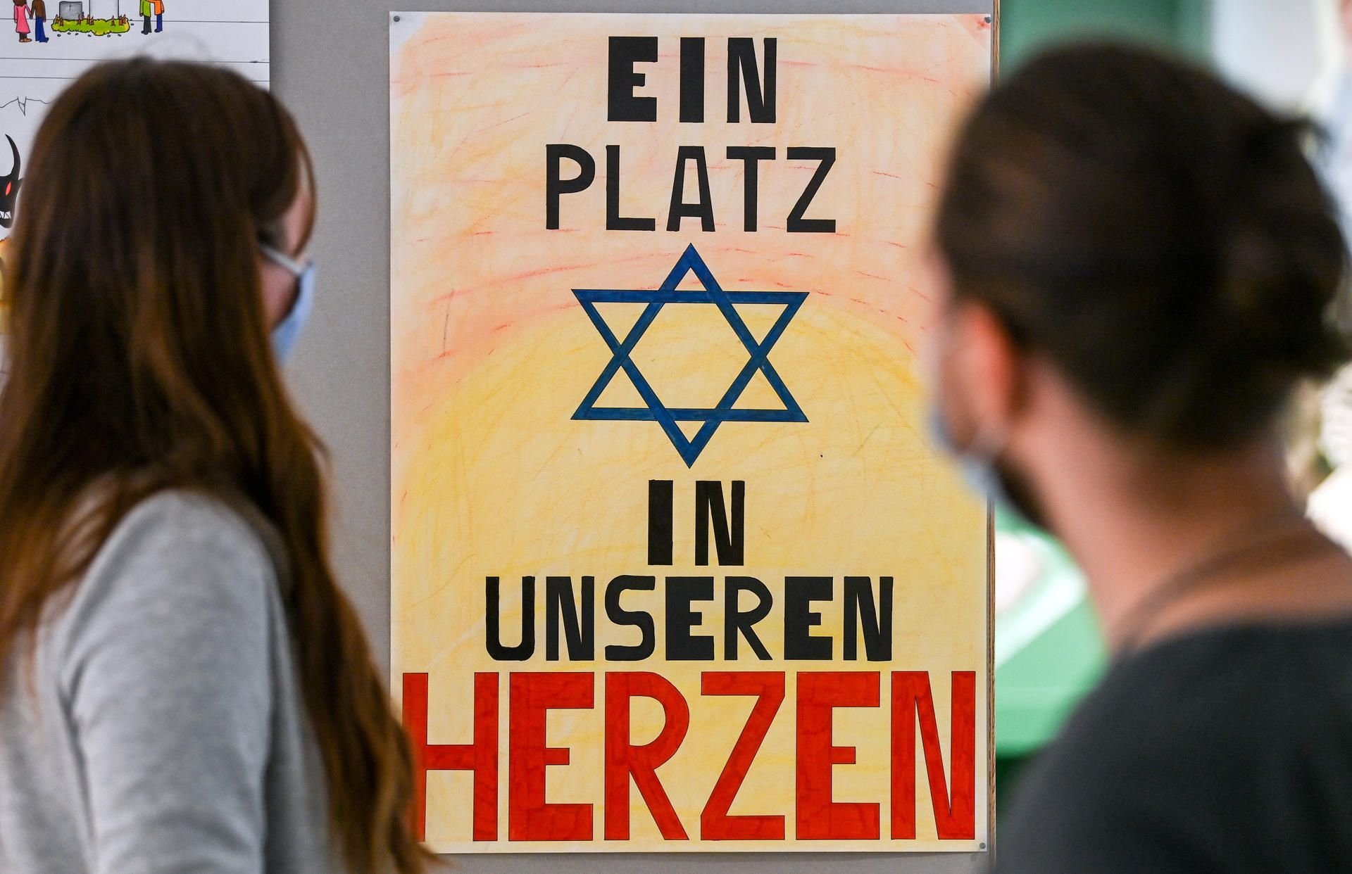 Berufsschüler betrachten im Stadtmuseum ein Plakat mit der Aufschrift "Ein Platz in unseren Herzen".