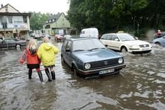 Mädchen in Gummistiefeln laufen am Freitag (15. Juli 2005) in Kassel durch eine nach unwetterartigem Regen vollgelaufene Straße. Das wolkenbruchartige Unwetter mit Hagel und Sturm hat in und um Kassel zahlreiche Bäume entwurzelt und den Verkehr behindert. (Foto: dpa)