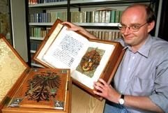 Der Direktor des Deutschen Adelsarchivs, Christoph Franke, präsentiert im Adelsarchiv in Marburg zwei Adelsdiplome (Urkunden in Schmuckform), im Hintergrund sind Ahnenforschungsbücher des Archivs zu sehen (Archivfoto vom 13.08.1998). (Foto: dpa)