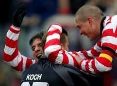 Zslot Löw (l) umarmt den Cottbusser Torwart Georg Koch bei einem Spiel im März 2004 - Christian Beek (r) jubelt mit (Foto: dpa).