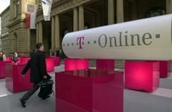 Ein Börsenhändler geht am 17.04.2000 durch die Werbung für den Börsengang der T-Online Aktie hindurch in die Frankfurter Wertpapierbörse (Archivbild). Die Aktien der Telekom-Internettochter wurden an diesem Tag erstmals an der Börse gehandelt. Der Ausgabepreis betrug 27 Euro. Die Deutsche Telekom nimmt ihre Internet-Tochter T-Online von der Börse und integriert sie in ihre Festnetzsparte T- Com. Die Anteilseigner sollen die Wahl zwischen einem Umtausch in Telekom-Aktien oder einer Barabfindung von 8,99 Euro je T-Online- Aktie haben, teilte das Unternehmen am Samstag (09.10.2004) mit. Die Verschmelzung solle voraussichtlich im zweiten Halbjahr 2005 wirksam werden. (Foto: dpa)