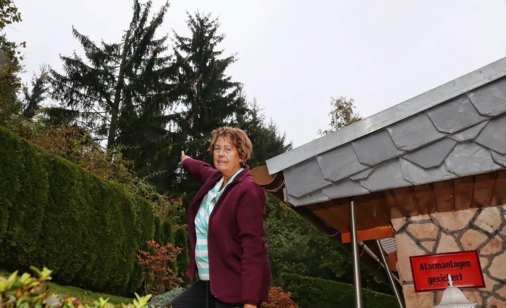 Gisela Sichting zeigt auf die hohen Fichten, die auf ihr Grundstück zu fallen drohen.