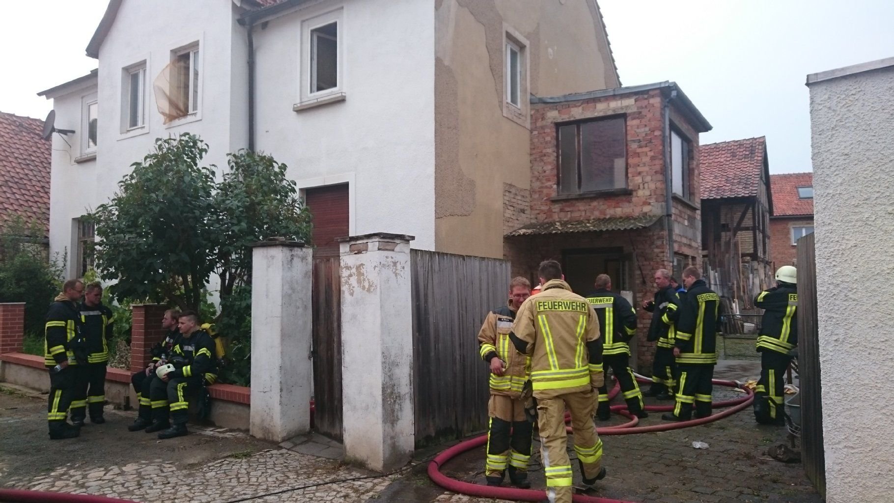 Feuerwehrleute stehen am 14. August 2015 vor dem Haus in Westerhausen, in dem sich der Brand ereignet hatte.