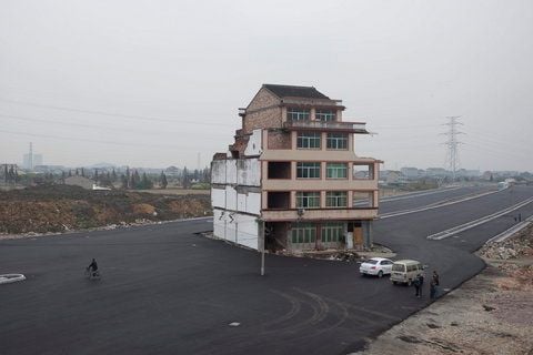 Ein fünfstöckiges Haus steht inmitten einer neu gebauten Straße in Wenling in China. Besitzer Luo Baogen und seine Ehefrau weigerten sich auszuziehen. Nun gaben die beiden nach und akzeptierten eine Entschädigung. (FOTO: DPA)