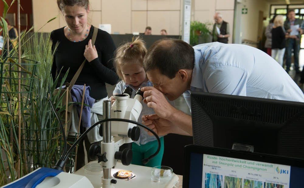 Das Pflanzen rosten können, ist kaum bekannt. Dazu hatte Albrecht Serfling (r.) ein Mikroskop aufgebaut, um den Befall an Getreide zu zeigen. Für alle Nachwuchsforscher legte der Wissenschaftler aber schon mal eine Tüte Gummibärchen unter das Gerät. Luise und Mama Josephine Engel gefiel die Idee.